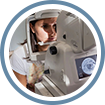 A woman is looking through the lens of an ophthalmoscope.